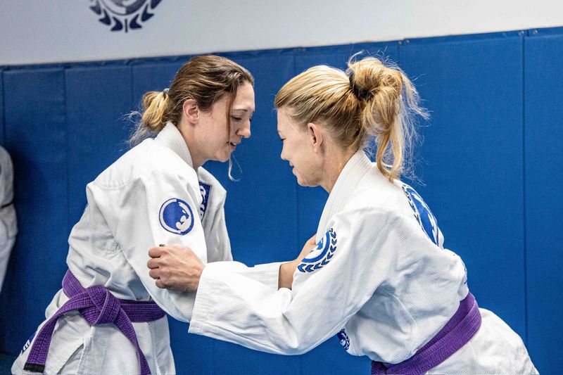 Two women gripping up from standing in a jiu jitsu class at Renzo Gracie Milford
